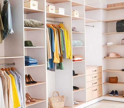Big wardrobe with clothes in dressing room